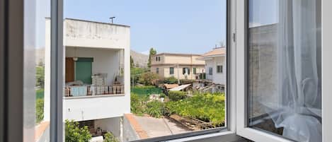 A view from a window overlooking a residential area with houses, a garden, and a clear sky.
