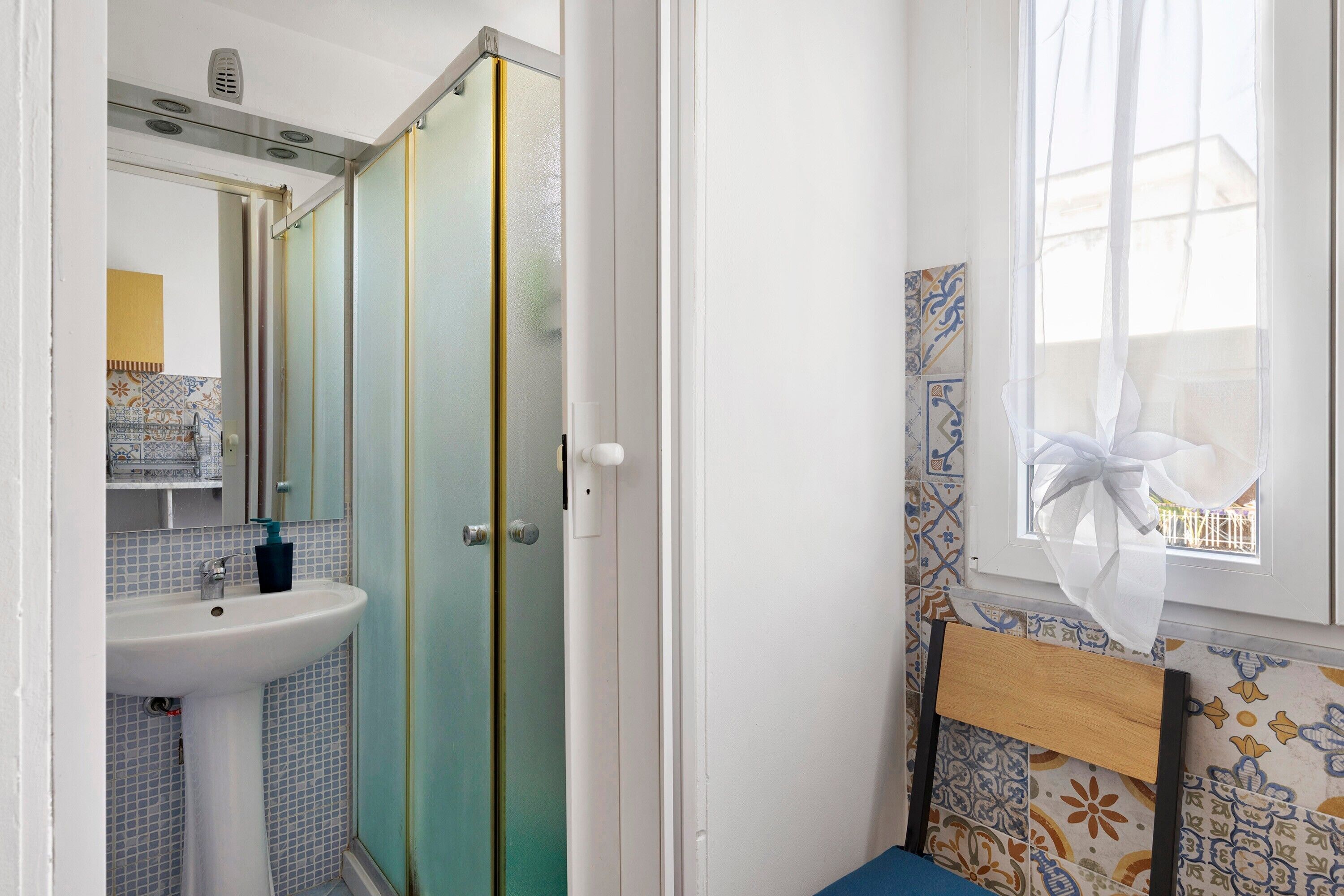 Baño con lavabo, espejo y cabina de ducha.