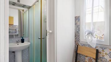 Baño con lavabo, espejo y cabina de ducha.