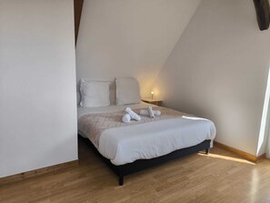 A bedroom with a bed, pillows, a nightstand, and a lamp.