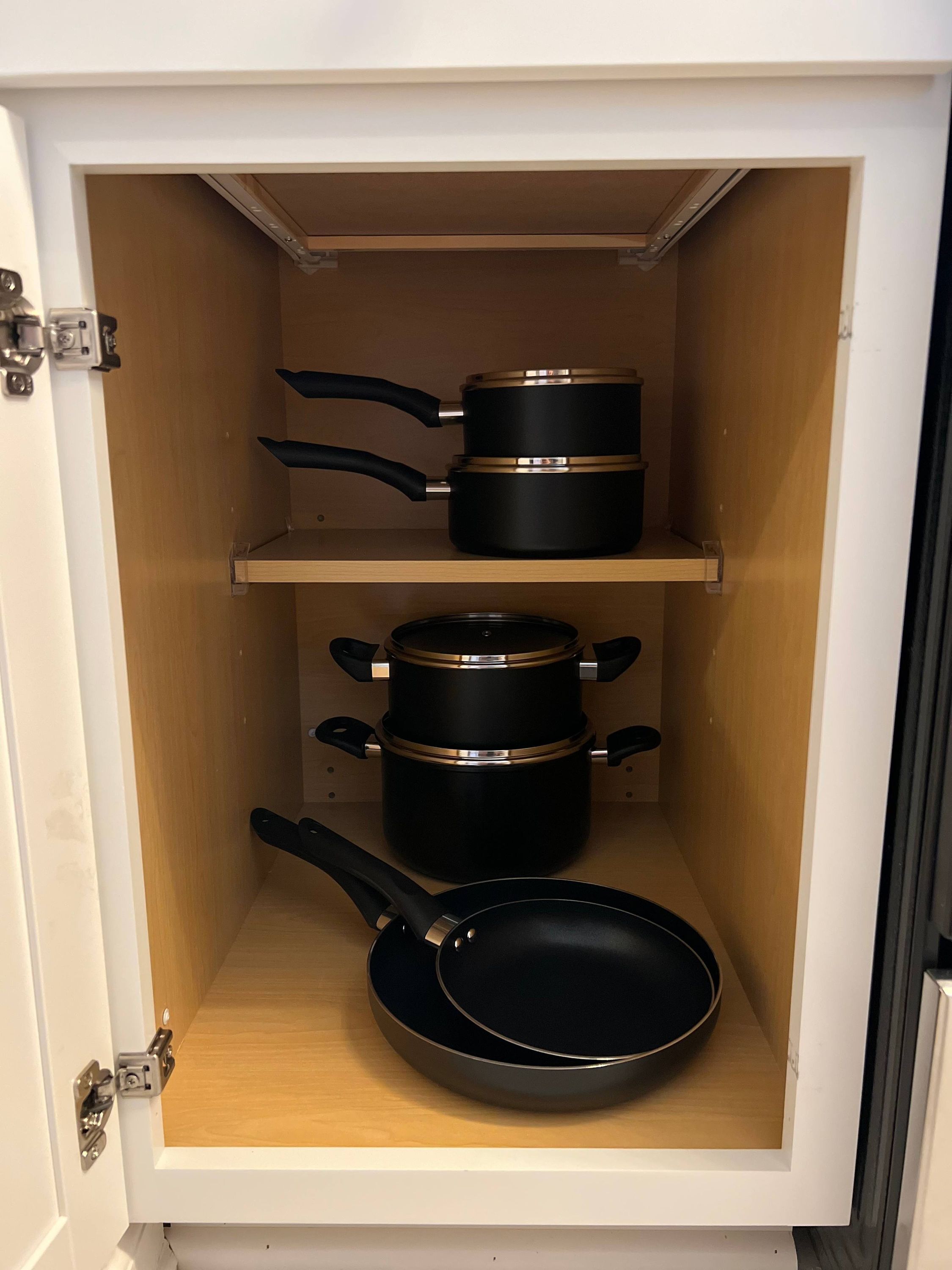 A kitchen cabinet with pots and pans.