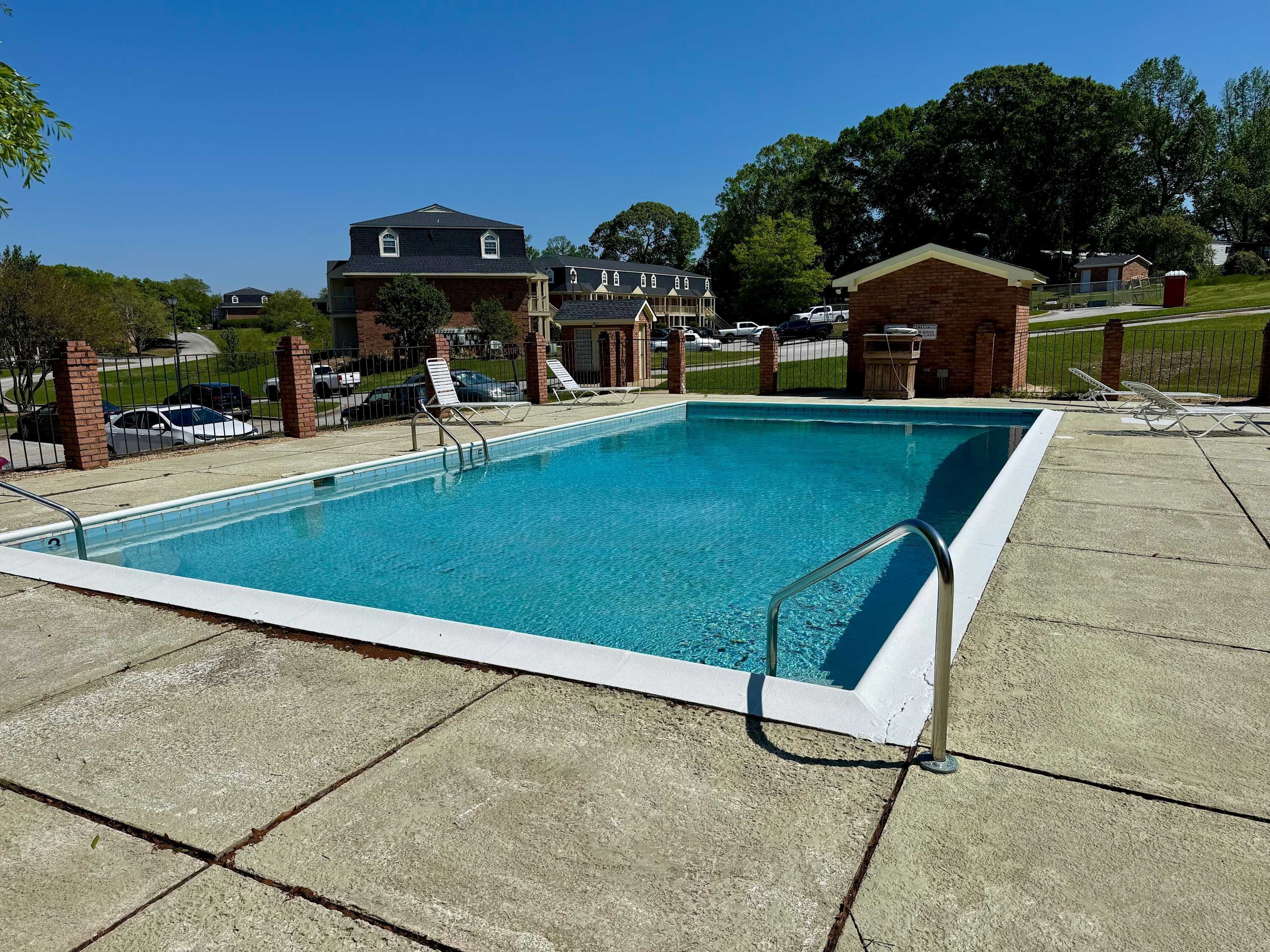 Piscina retangular com borda branca, rodeada por um deck de concreto.