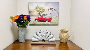 A wooden table with a vase of flowers, a decorative metal piece, and a painting of a red truck.