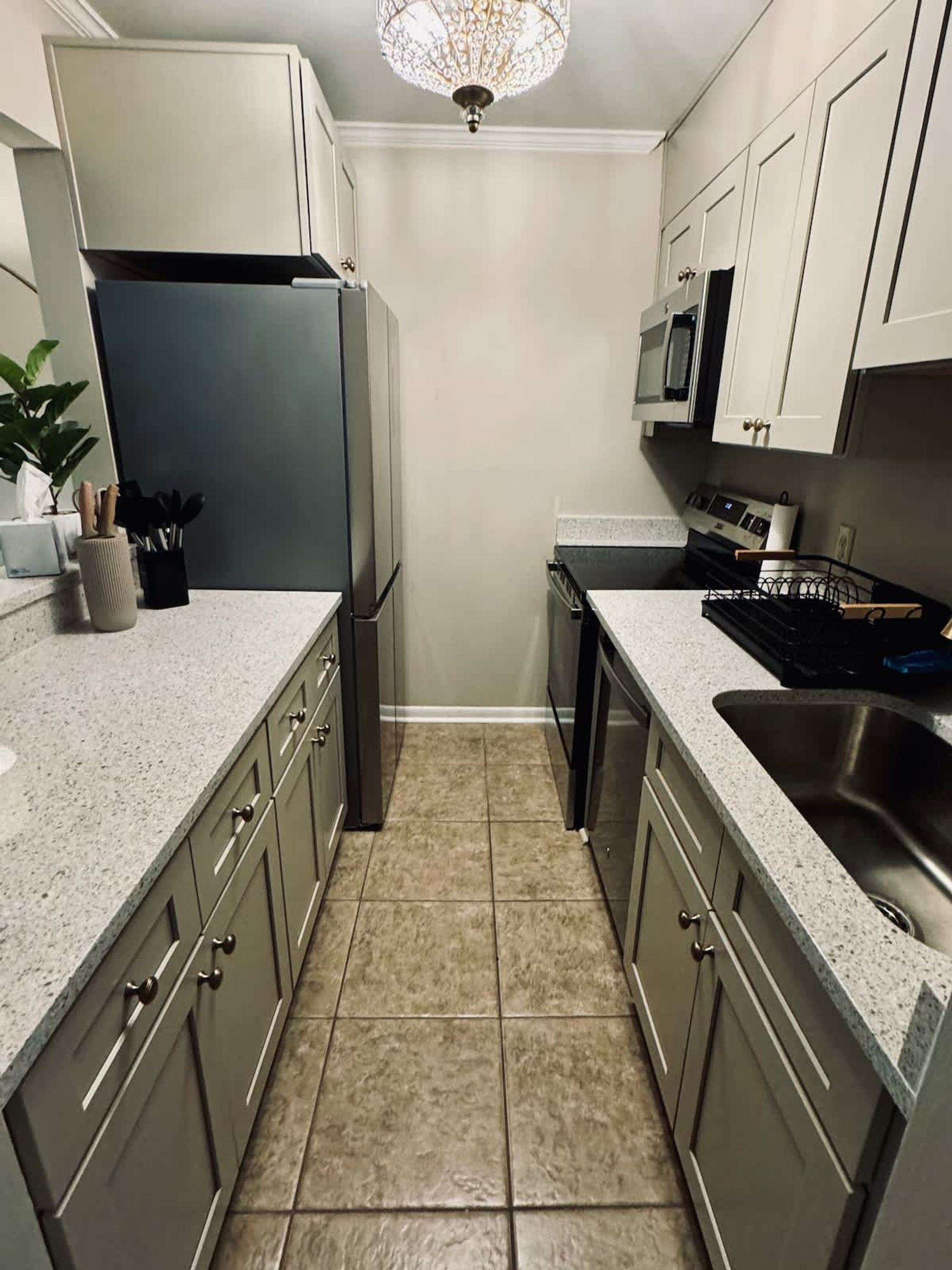 A kitchen with a refrigerator, microwave, stove, sink, and cabinets.