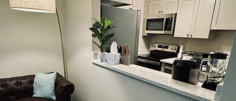 Un salón moderno con un sofá de cuero marrón, una mesita y un espejo sobre una encimera de cocina.
