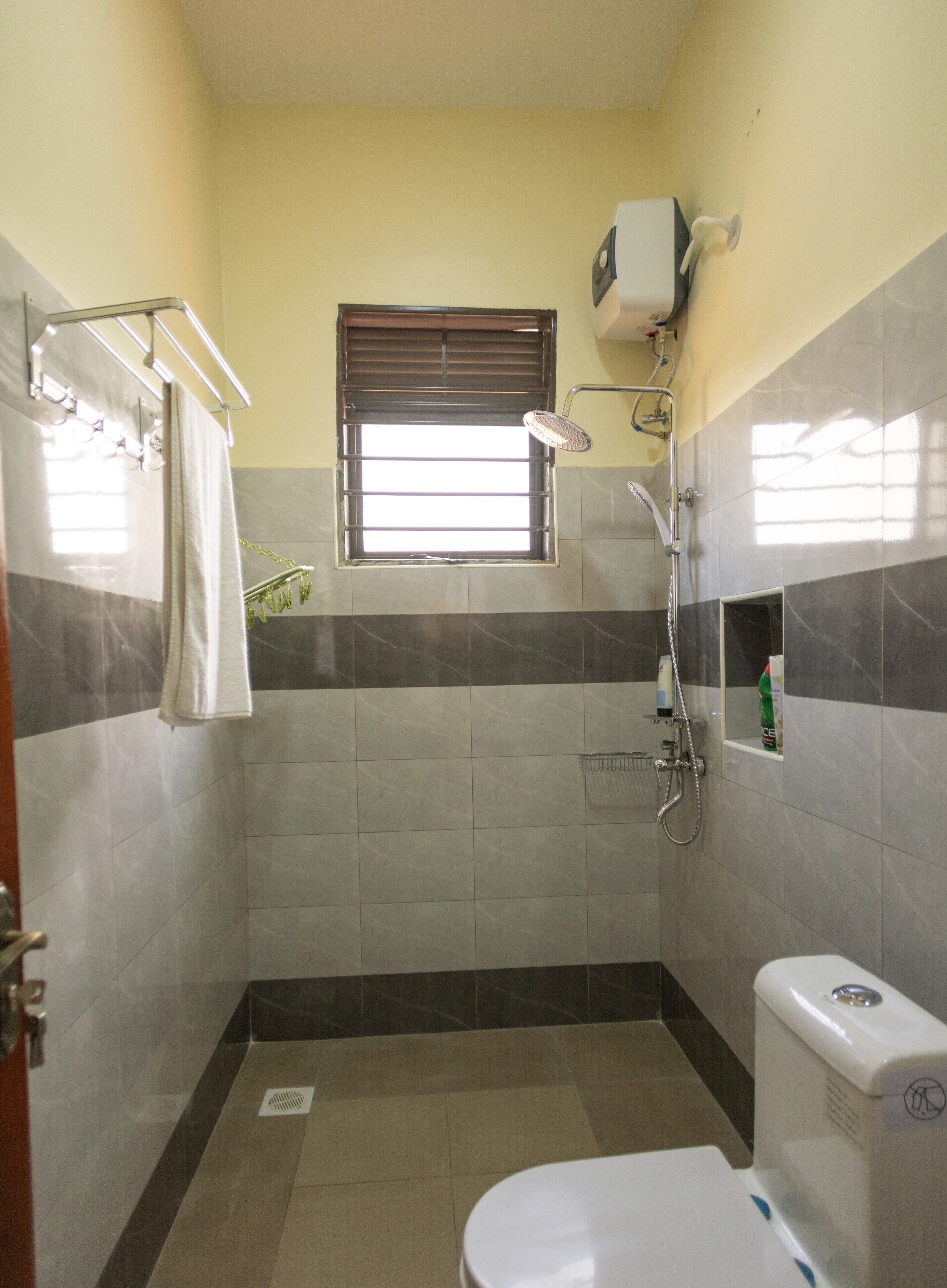 A bathroom with a shower, toilet, and a window.
