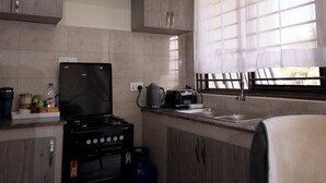 Una kitchenette compacta con estufa a gas, hervidor y tostadora.