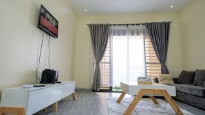 Una sala de estar moderna con un mueble blanco para entretenimiento, un sofá gris y una mesa de centro.