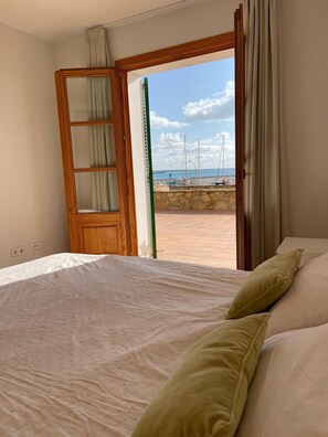 Ein Schlafzimmer mit Bett, einem Holzschrank und Blick auf den Strand mit Segelbooten.