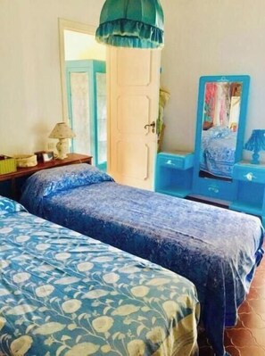 A bedroom with two beds, a dresser, a mirror, and a door. - Spacious apartment in a villa with a fully equipped garden and a rooftop with a panoramic view (Procida)