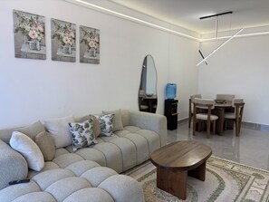 A modern living room with a sectional sofa, a coffee table, a dining area with a table and chairs, and artwork on the wall. - Serene 2-bedroom apartment perfect for your Nairobi getaway (Nairobi)