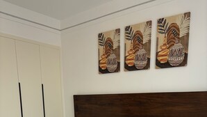 Ein Schlafzimmer mit einem großen Bett, einem hölzernen Kopfteil, einem Kleiderschrank und drei an der Wand befestigten Bildern.