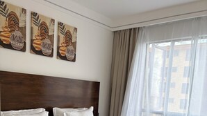 Ein Schlafzimmer mit hölzernem Kopfteil, weißer Bettwäsche, einem gemusterten Teppich und Bildern an der Wand.