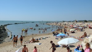 Uma praia movimentada com pessoas se banhando e tomando sol.