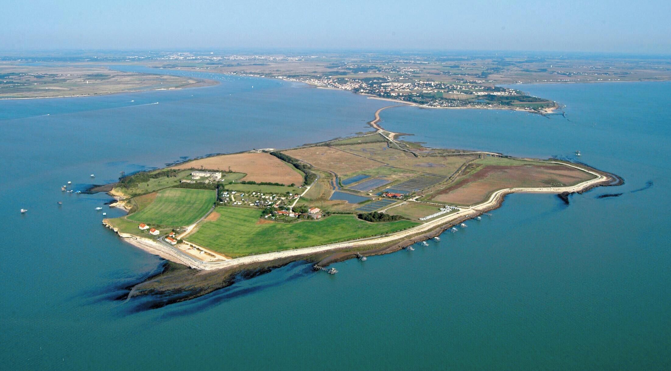 An aerial view of an island with a mix of residential and agricultural areas, surrounded by water.