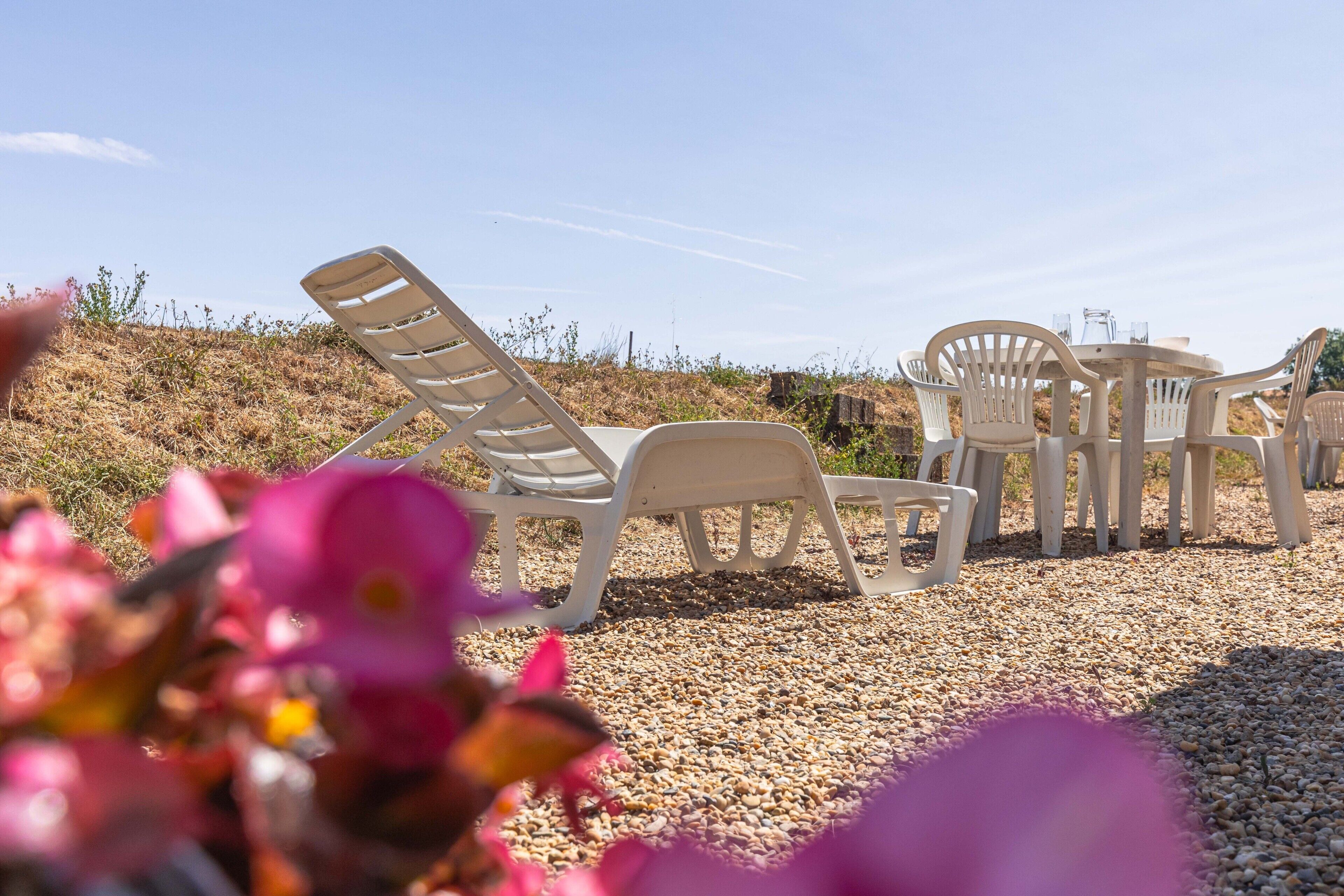 Espace extérieur aménagé avec des chaises et une table, un sol en gravier et un ciel dégagé.