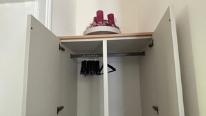 Un armadio bianco con un'asta appendiabiti e uno scaffale circolare nella parte superiore.
