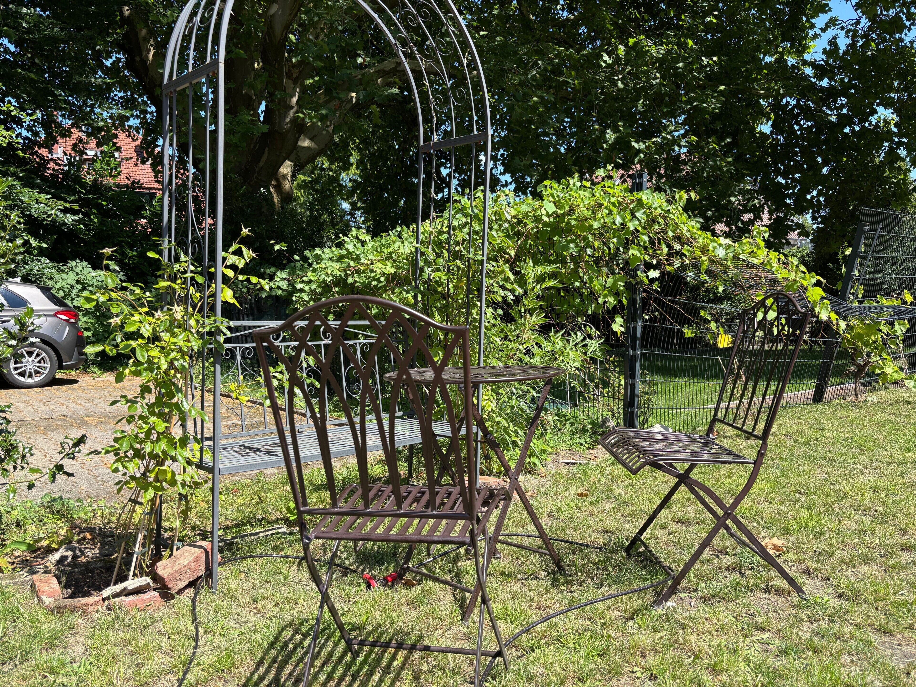 Un jardín con sillas y un arco de metal.