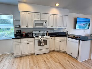 A modern kitchen with white cabinets, a microwave, stove, and a sink. - Rotonda West Escape with Pool, BBQ, Bikes and Beach Gear Near Boca Grande (Rotonda West)