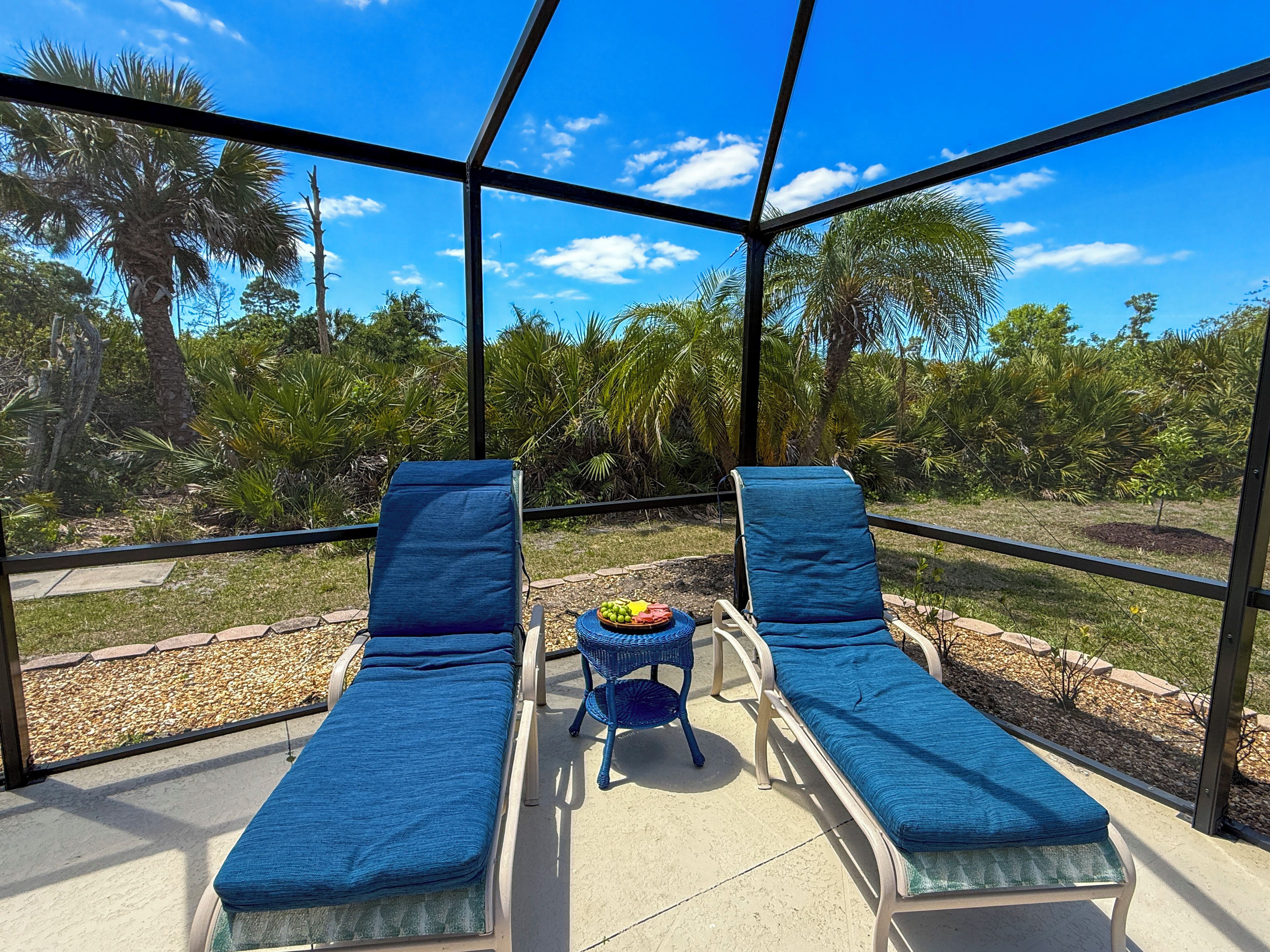 Un solárium con dos sillones de descanso, una mesita con fruta y vistas a un jardín tropical.