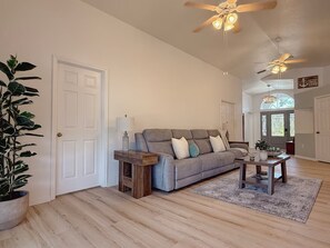 A spacious living room with a grey sofa, wooden coffee table, and a ceiling fan. - Rotonda West Escape with Pool, BBQ, Bikes and Beach Gear Near Boca Grande (Rotonda West)