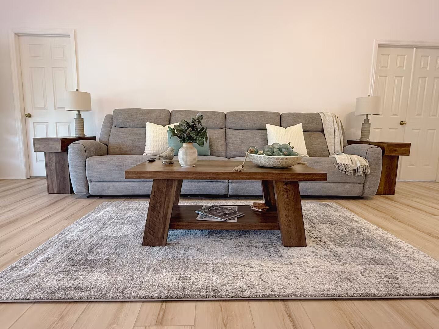 Ein Wohnzimmer mit grauem Sofa, einem Holztisch und einem grauen Teppich.