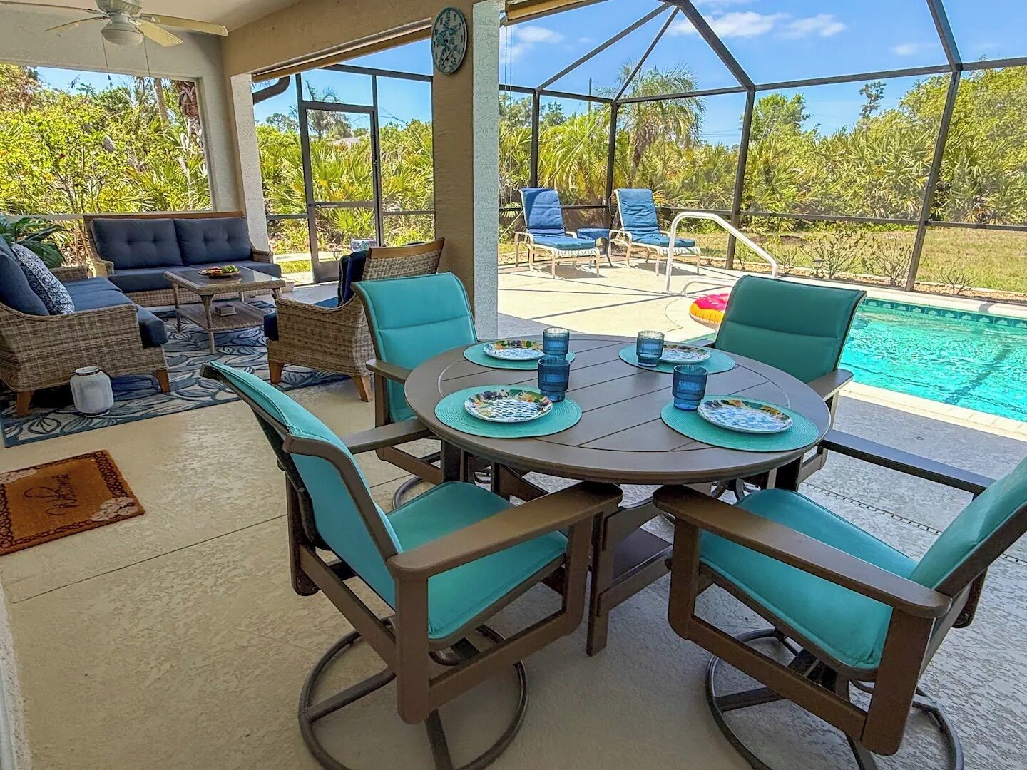 A covered outdoor area with a pool, seating, and a dining table set for four.