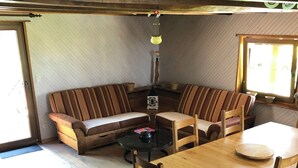 Tunnelmallinen huone, jossa on puinen pöytä, tuoleja, raidallinen sohva ja lamppu.