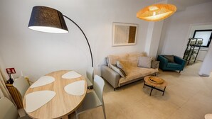 Una sala de estar moderna con una mesa redonda, dos sofás, una mesa de centro y una lámpara de pie grande.