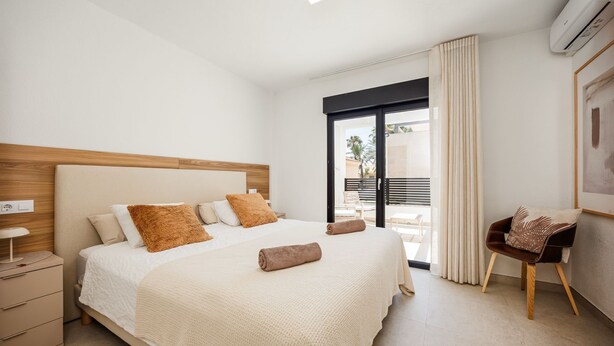 Habitación de hotel con cama, una silla, una mesita de noche y vistas al exterior.