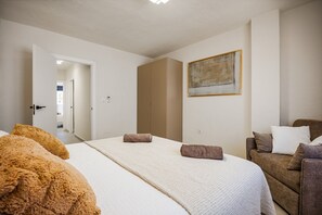 Et hotelværelse med en seng, en sofa, et billede på væggen og en dør til et andet rum.