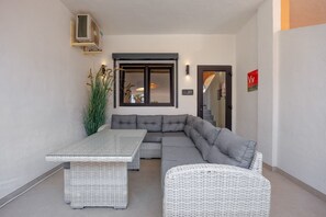 Ein moderner Außenbereich mit Ecksofa, Esstisch und Korbmöbeln.