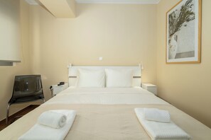 Ein Hotelzimmer mit einem Bett, zwei Nachttischen, einem Sessel und einem gerahmten Bild an der Wand.