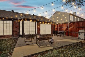 A backyard patio with string lights, a grill, and outdoor seating. - Fireside Retreat| Sleeps 10 | Foosball | Fire pit (Grand Prairie)