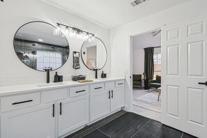 Een moderne badkamer met een grote spiegel, een wastafel en een douchehoek.