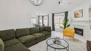 A living room with a sectional sofa, a yellow armchair, a round coffee table, and a fireplace. - Fireside Retreat| Sleeps 10 | Foosball | Fire pit (Grand Prairie)