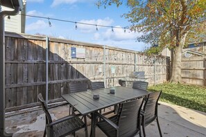 Eine Terrasse mit Tisch, Stühlen, einem Grill und einem Holzzaun.