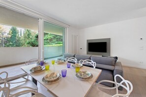 Un salon moderne avec un canapé, un téléviseur à écran plat et un coin repas avec une table mise pour deux personnes.