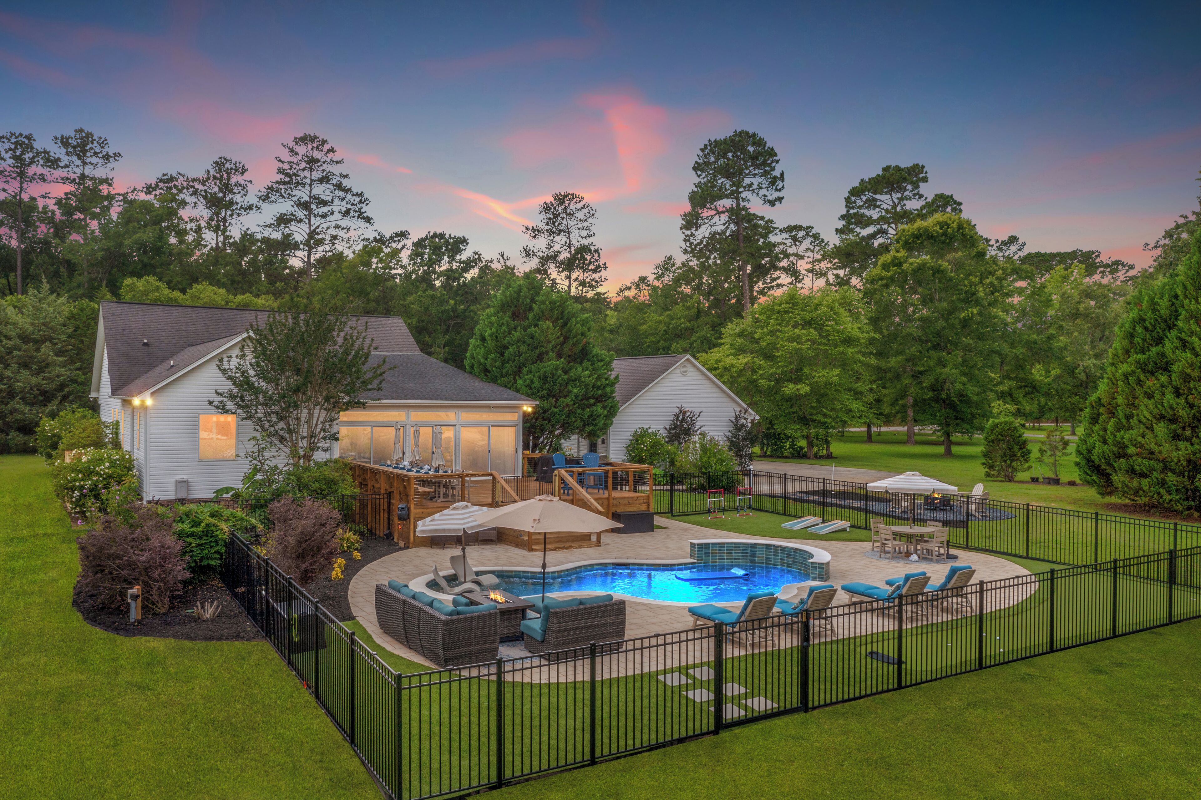 A residential backyard with a swimming pool, outdoor furniture, and a fenced area.