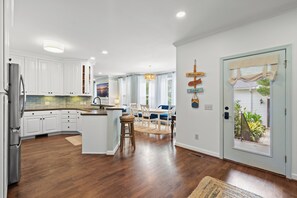 A modern kitchen with white cabinets, a central island, and a dining area with a view of the outdoors. - Beautiful-Lakefront Farmhouse Retreat w/ Pool (Summerton)