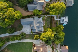 An aerial view of a residential area with houses, a dock, and a body of water. - Big Water Lodge | Hot Tub, Fire Pit, & Lake Views (Macon)