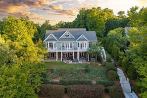 A large house with a covered patio and a staircase leading to a second level. - Big Water Lodge | Hot Tub, Fire Pit, & Lake Views (Macon)