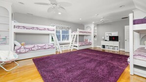 A child's bedroom with bunk beds, a purple rug, a white desk, and a ceiling fan. - Big Water Lodge | Hot Tub, Fire Pit, & Lake Views (Macon)