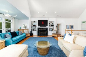 A spacious living room with a fireplace, a television, and a large window. - Big Water Lodge | Hot Tub, Fire Pit, & Lake Views (Macon)