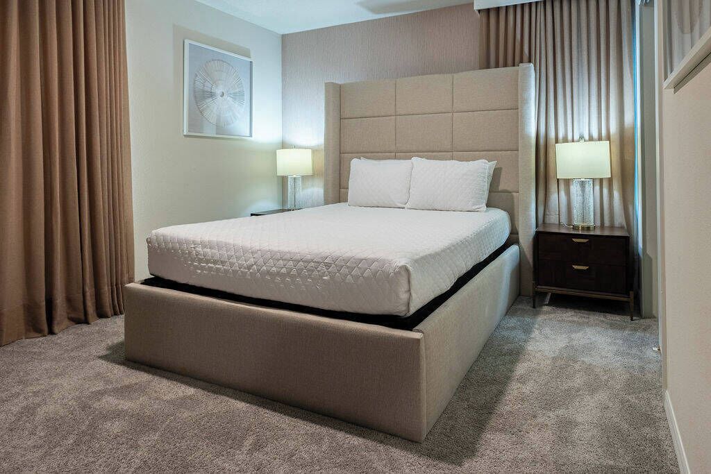 Ein Hotelzimmer mit einem gro ßen Bett, einem Nachttisch, einer Lampe und einem Wandbild.