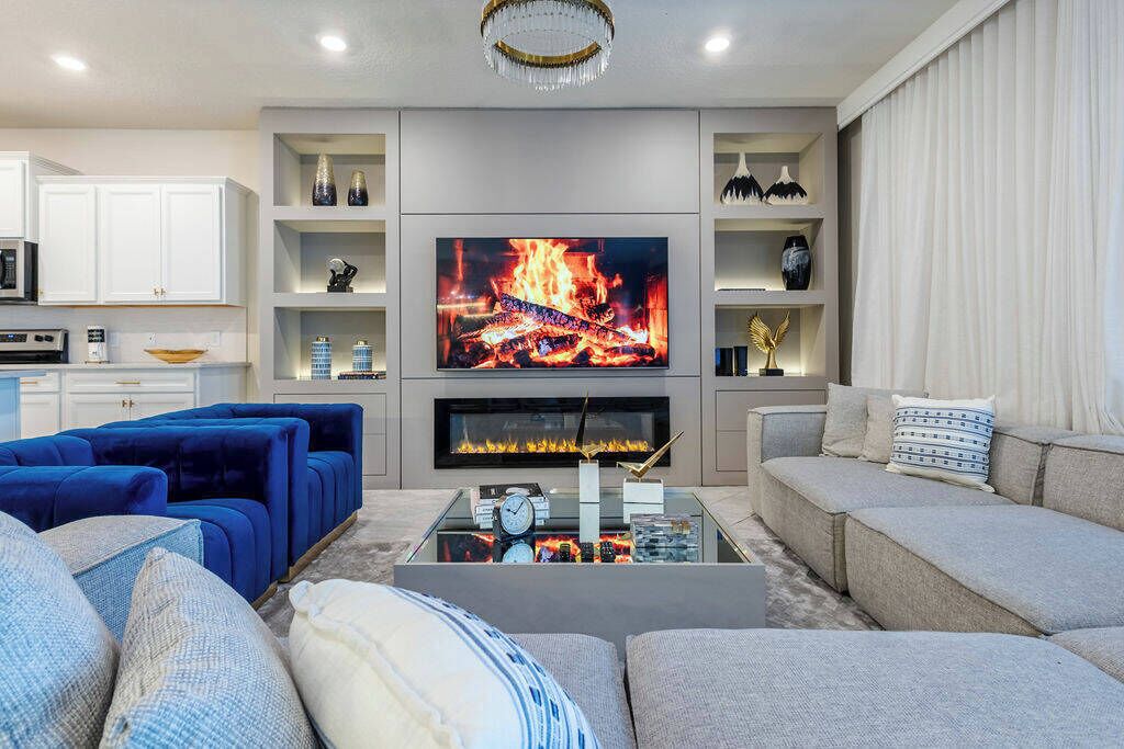 A modern living room with a fireplace, a flat-screen TV, and a cozy seating area.