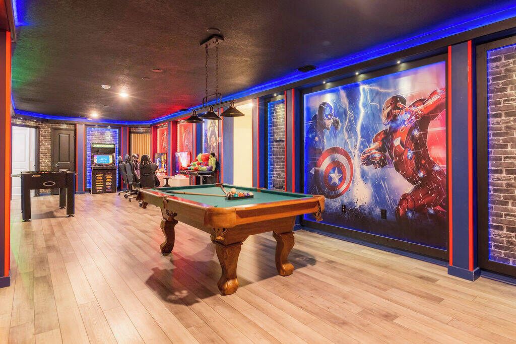 Een pooltafel in een ruimte met een bakstenen muur en een groot Captain America poster.