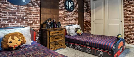 A bedroom with two beds, a dresser, and a door.