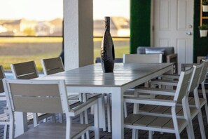 Ein Essbereich im Freien mit einem langen Tisch, mehreren Stühlen, einer dekorativen Vase und Blick auf die Landschaft.