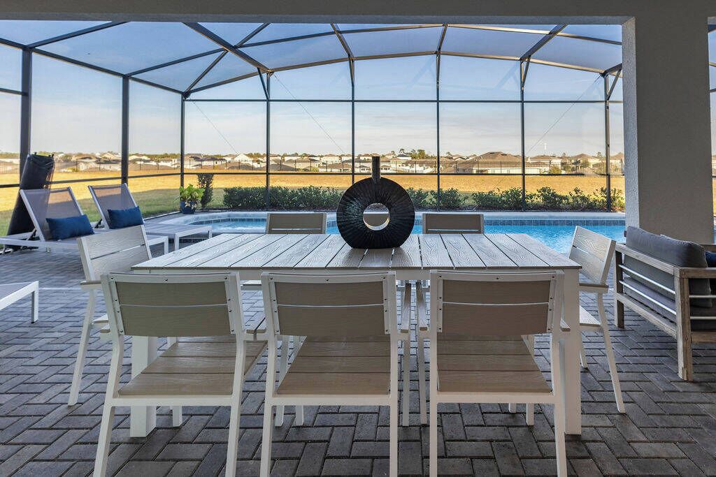 Une terrasse extérieure couverte, dotée d’une piscine, de coins salon et offrant une vue sur le paysage.